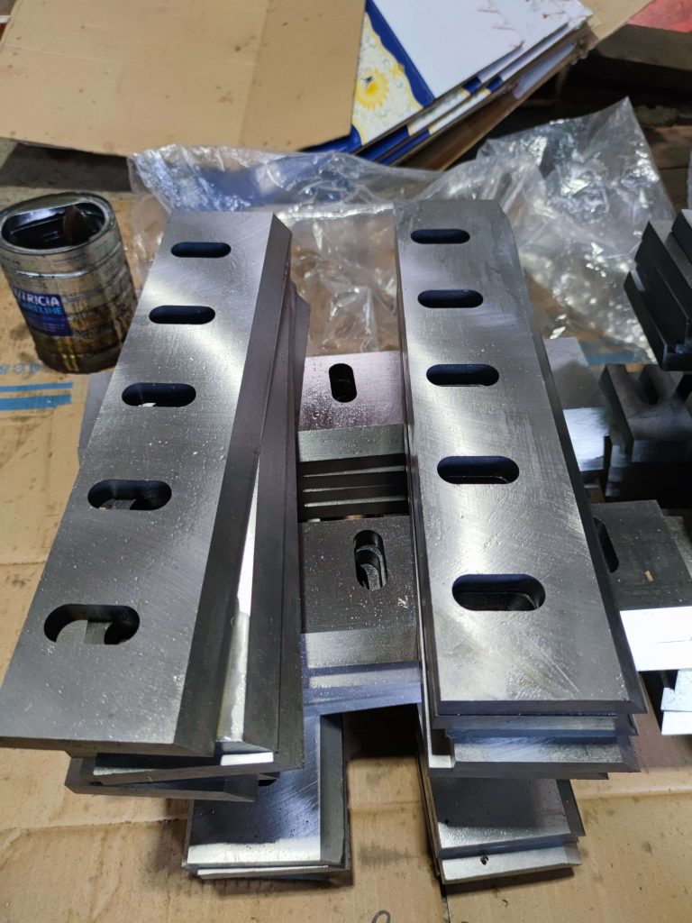Precision-ground crusher blades arranged on a workshop bench